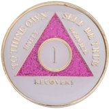 Alcoholics Anonymous recovery coin with pink triangle and gold text on a white background