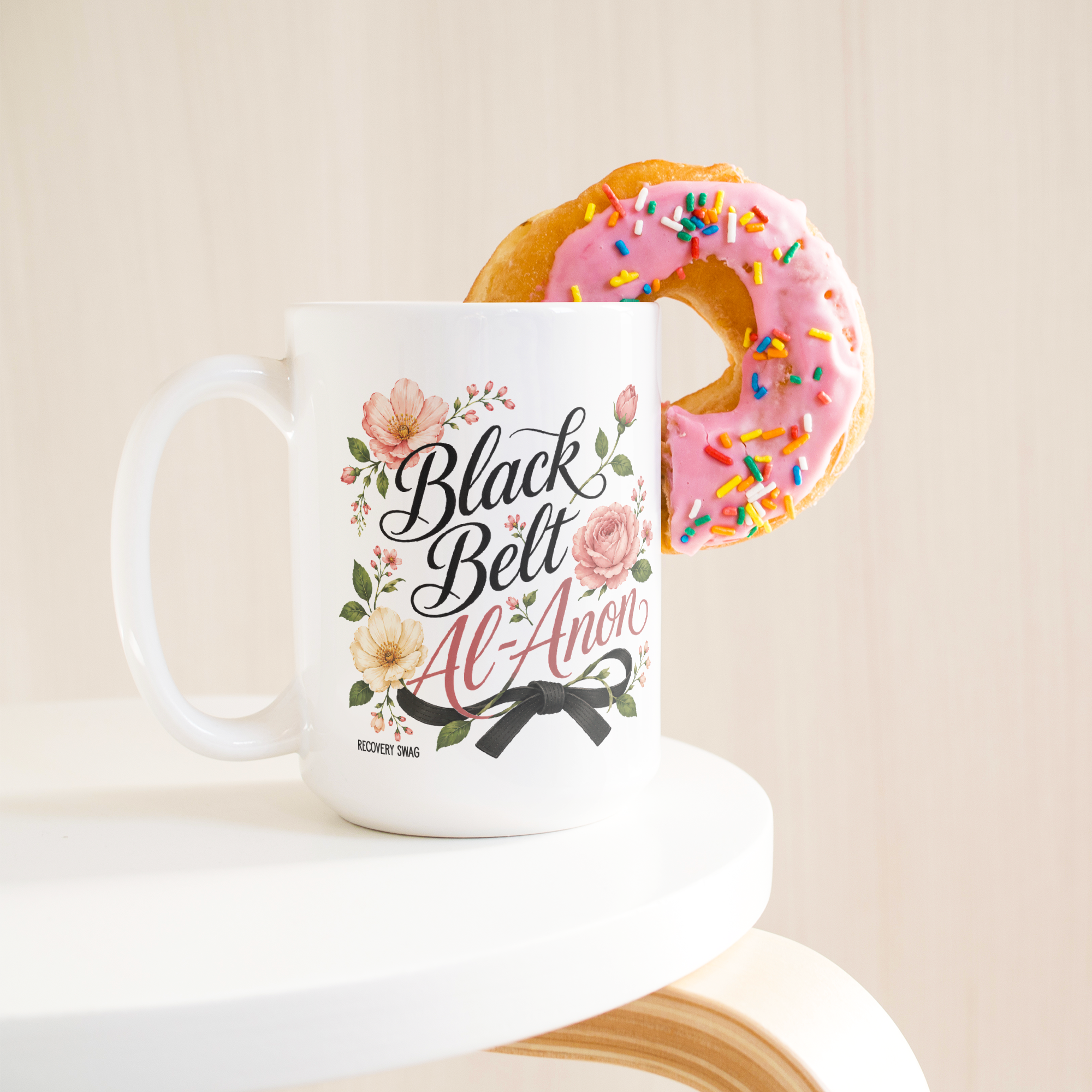 Black_Belt_Al-Anon_Recovery_Coffee_Mug__15ozWhiteMugLifetsyleDonutLH_Mockup.png_15824891